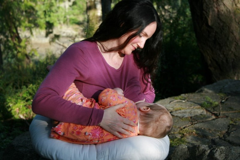 content mother nursing a baby laying on a nursing pillow filled with natural eco wool and encased in organic cotton sateen