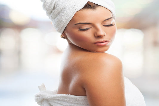 Peaceful attractive woman looking over her right shoulder and wrapped in a White Colored Luxurious Bamboo Cotton Bath Towel and her brown hair wrapped in a matching Luxurious Bamboo Cotton Bath Twoel