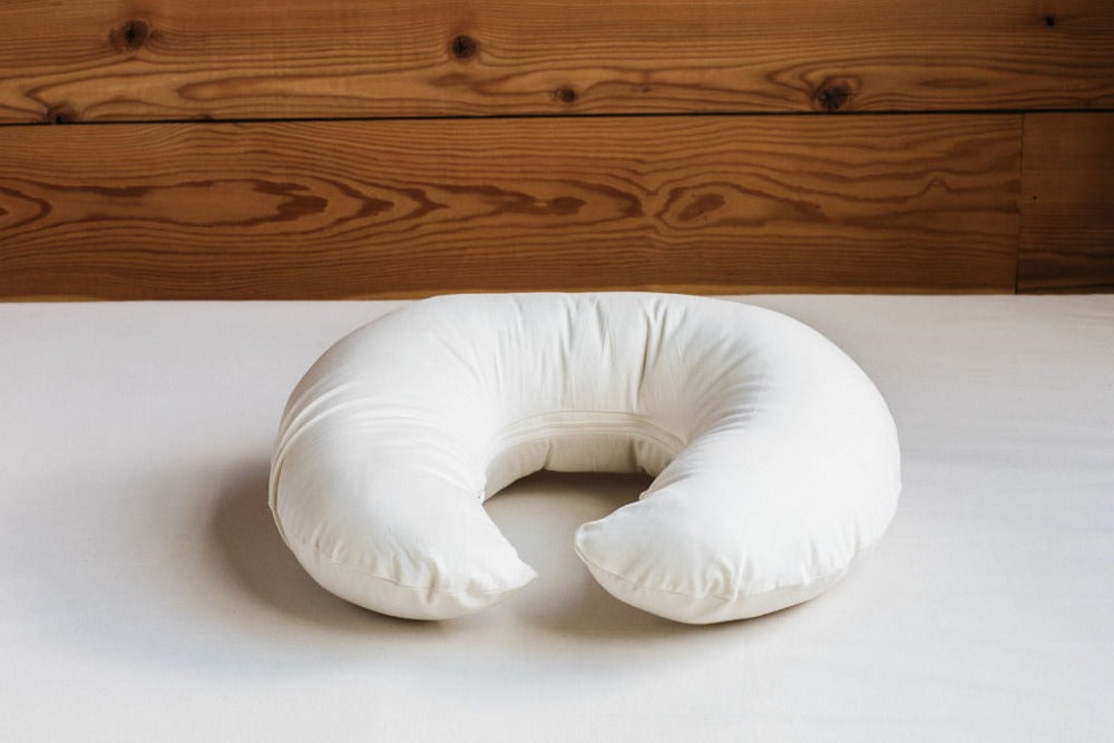 mother's nursing pillow filled with premium eco wool and encased in organic cotton sateen displayed on a bed