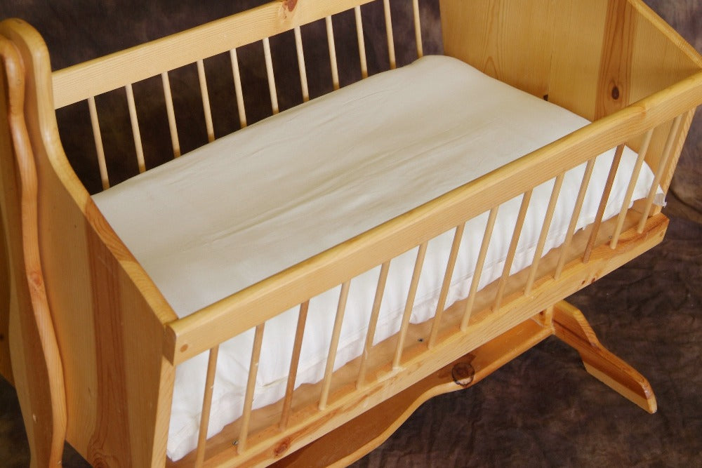 wooden bassinet with a premium eco wool filled mattress wrapped in an organic cotton sateen sheet