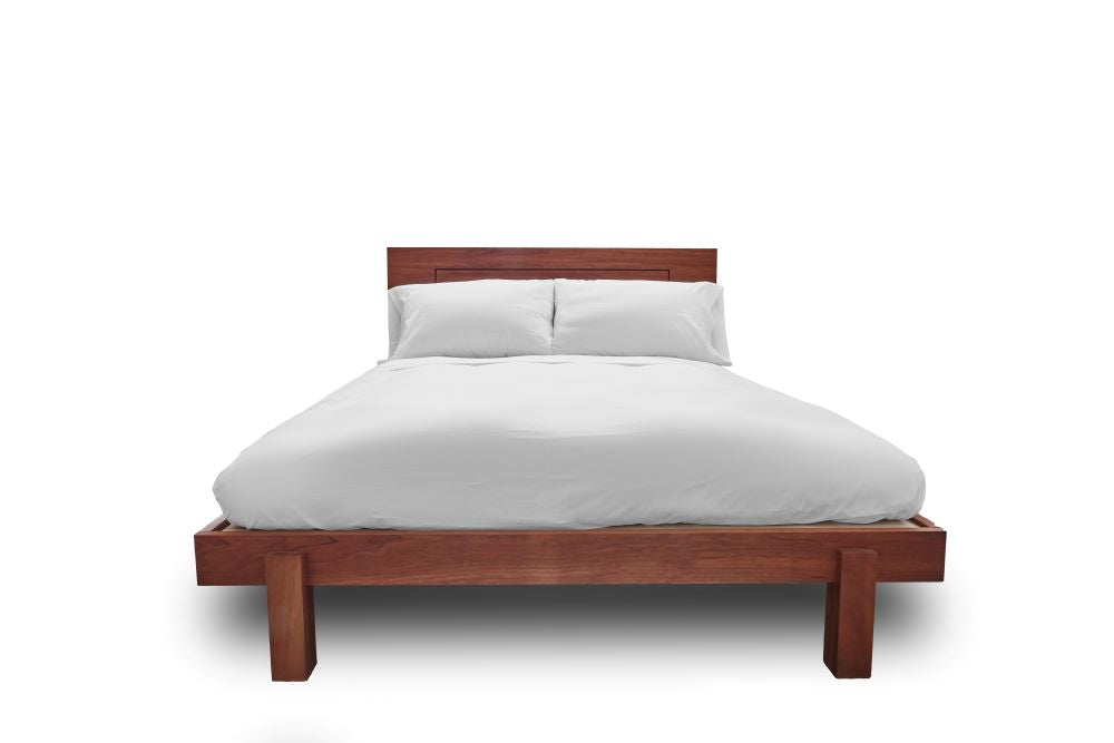 queen size wood frame bed covered with an organic cotton comforter and two natural latex stuffed sleep pillows propped against the headboard with a white background