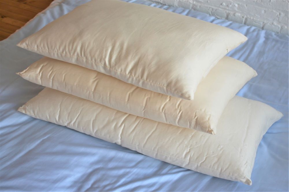 stack of three organic pillows displayed on bed 