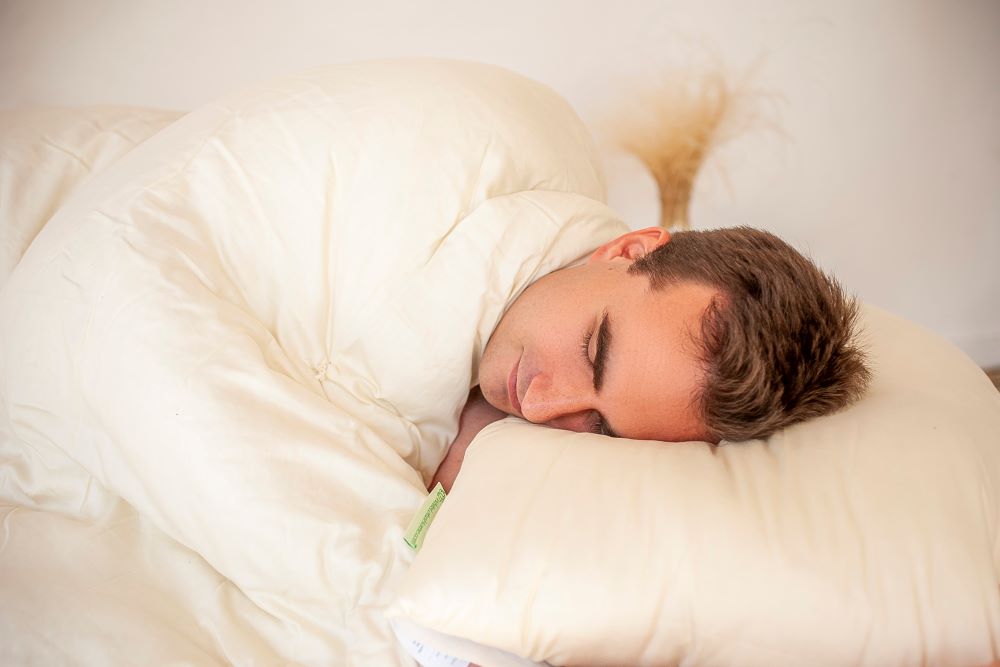 handsome man in deep sleep resting his head on an eco wool filled sleep pillow