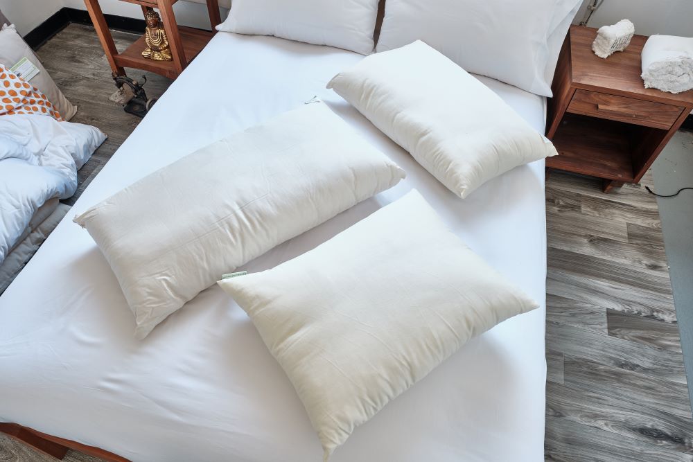 three various size organic cotton sleep pillows displayed on unmade bed
