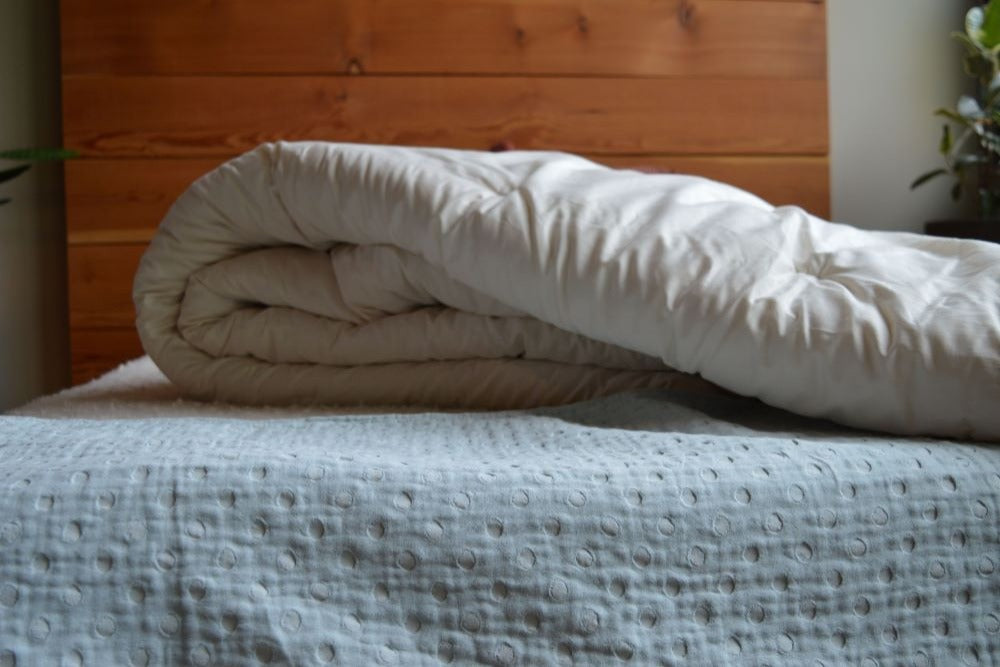 a half folded certified organic cotton comforter lying on a bed in a well decorated room