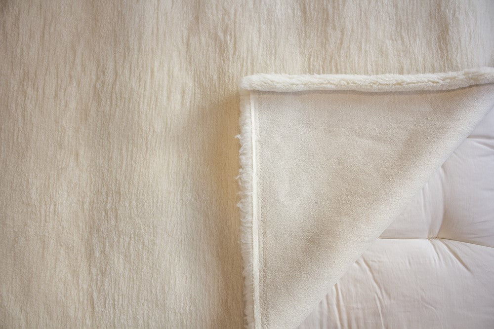 close up of natural happy lamb fleece displayed on a bed with the corner turned back