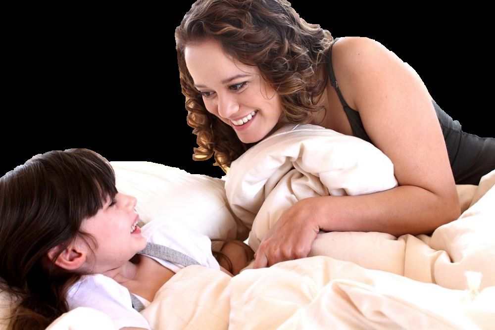 playful mom and daughter laying on bed scrunching up the sustainably sourced bedding