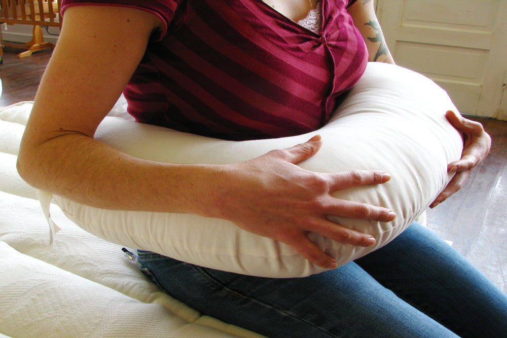 a mother demonstrating the use of a natural eco wool filled nursing pillow encased with organic cotton