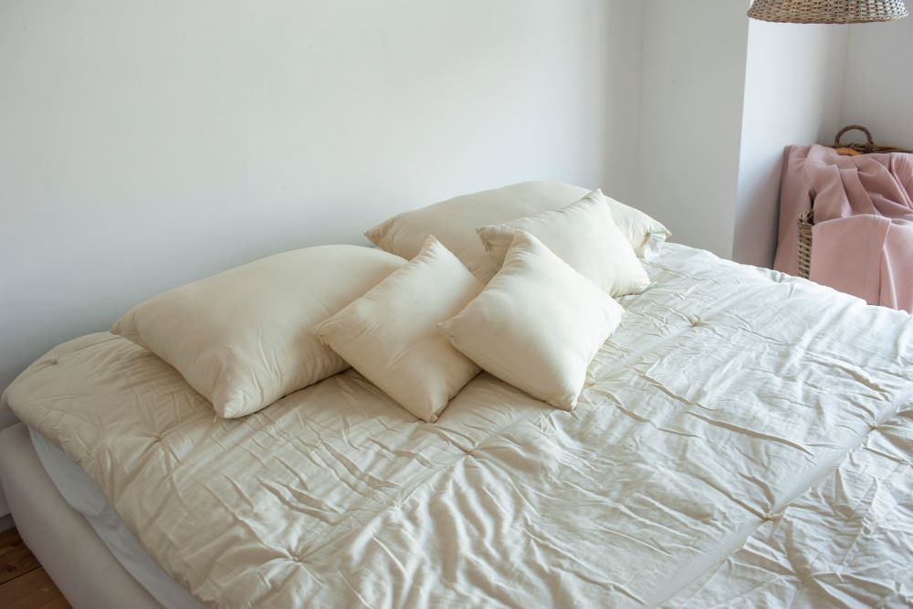 five down alternative pillows filled with sustainably sourced kapok laying on a clean unmade bed covered with an organic cotton comforter