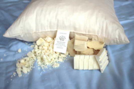 all natural latex filled sleep pillow displayed on blue sateen cotton with a sample of natural latex stuffing material in front of the pillow